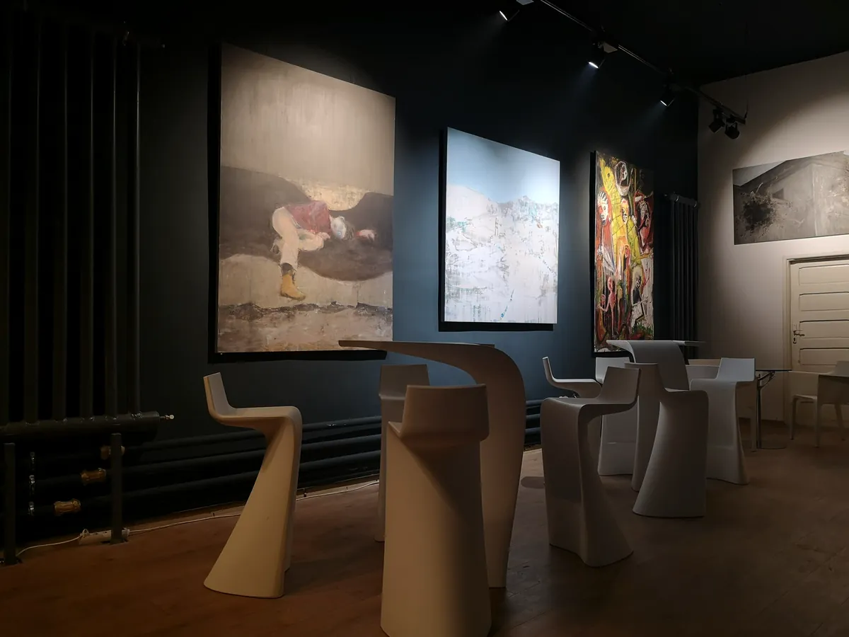 Original artwork displayed in the dark-toned interior of ArtHalle Bistro.
