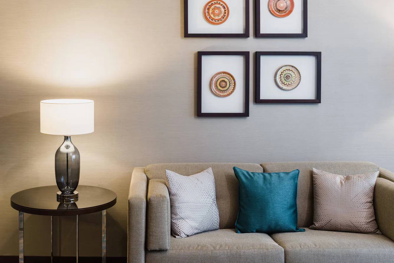 Four individually patterned ceramic works presented as a framed composition above a hotel sofa.