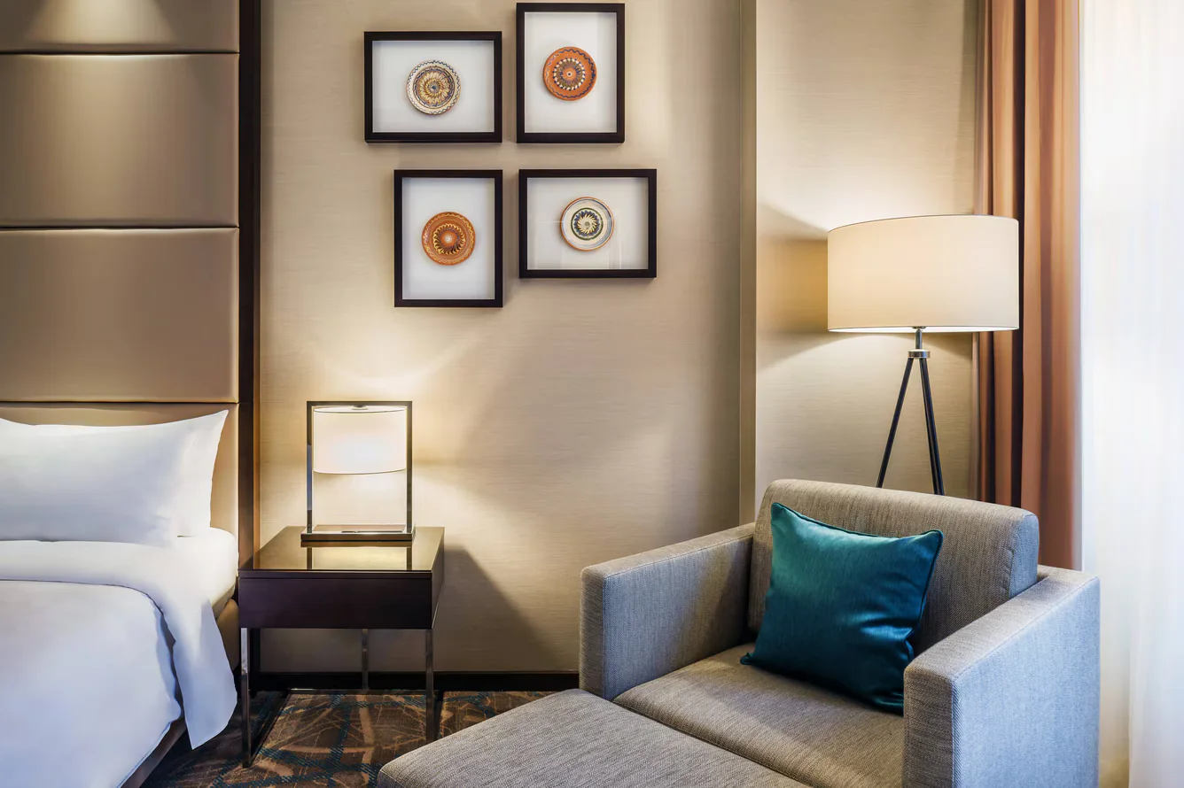 Close guestroom view with four framed ceramic works beside the bed and reading chair.